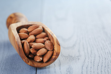 roasted almonds in measuring scoop on blue wooden table