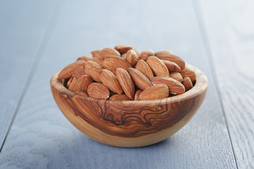 roasted almonds in bowl on blue wooden table