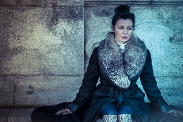 Sad Russian woman in fur coat in a park in autumn