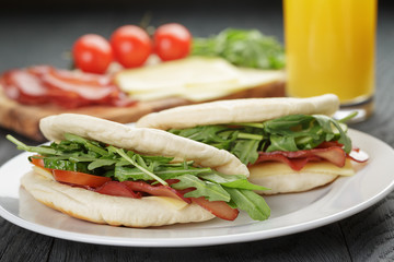two sandwiches with ham arugula and tomatoes in pita bread on