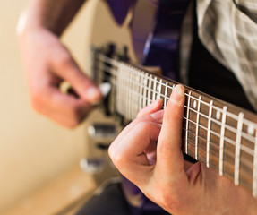 Fototapeta premium Praktyka gry na gitarze elektrycznej. Przystojni młodzi mężczyźni grają