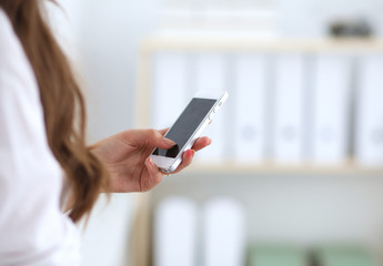 Businesswoman sending message with smartphone sitting in the