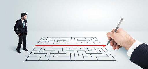 Business man looking at hand drawing solution for maze