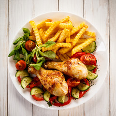 Grilled chicken drumsticks with chips and vegetables 