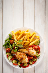 Grilled chicken drumsticks with chips and vegetables 