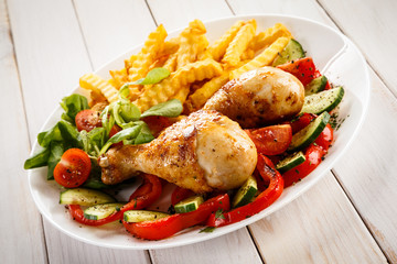 Grilled chicken drumsticks with chips and vegetables 