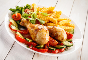Grilled chicken drumsticks with chips and vegetables 