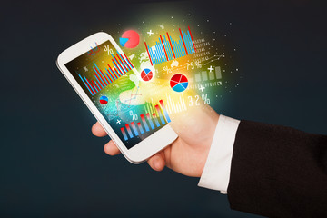 Business man holding smartphone with chart symbols