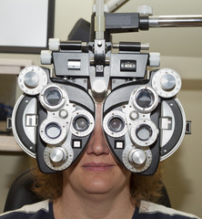 female getting an eye examination with a phoropter