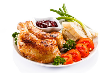 Grilled chicken legs and vegetables on white background