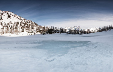 Lago alpino ghiacciato all'alba