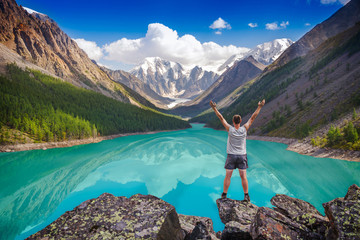 Hiker standing with raised hands near beautiful mountain lake
