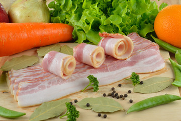 Sliced Bacon with herbs on the wooden bckground