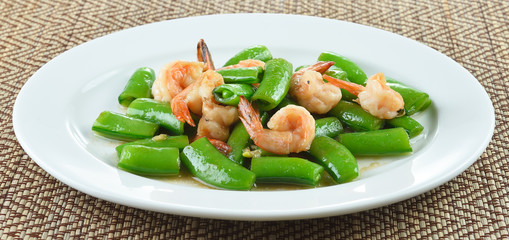 Stir-fried green  peas with shrimp on a white  plate.
