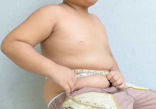 Fat boy measuring his belly with measurement tape