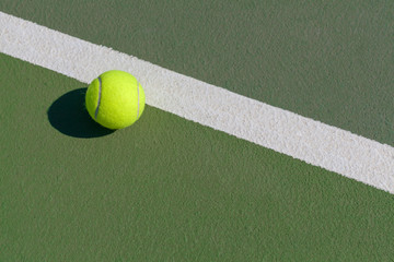 tennis ball next to line on hard court