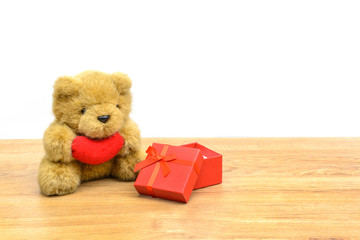 Red gift box and teddy bear on wooden table