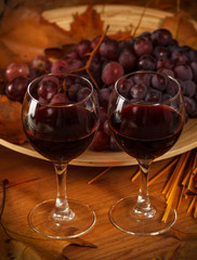 Two glasses of red wine with grapes.