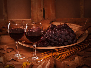 Two glasses of red wine with grapes.