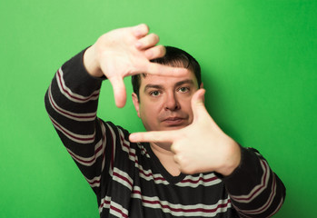man looking through the hands of the frame on a green background