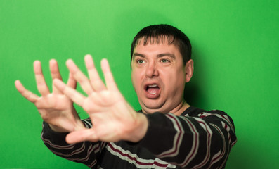 man is afraid gesture, hands on a green background