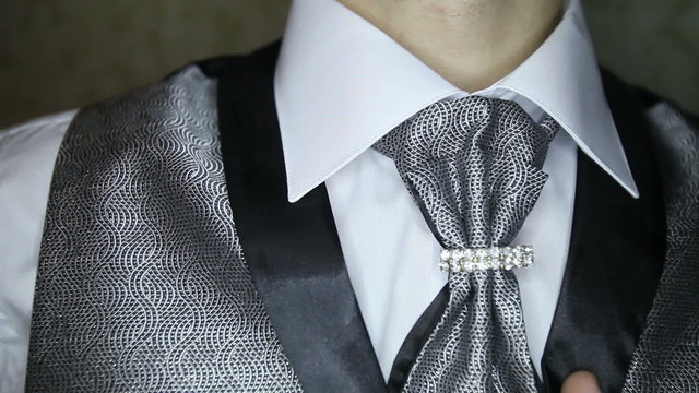 groom dark silver vest corrects brooch on dark silver necktie	