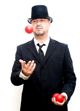 Businessman  with a hat  that is juggling with a red balls