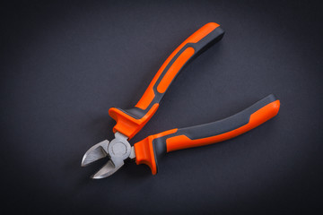 opened nippers with orange handles aerial view on black backgrou