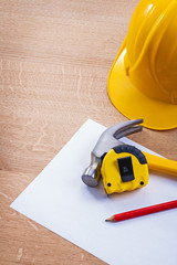 pencil tapeline hammer paper helmet on wooden board