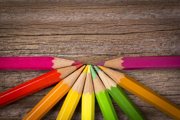 Naklejka premium Coloured pencils on wooden background