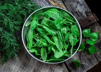 Garden sorrel in a bowl on wooden table.