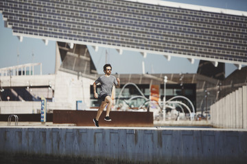 Naklejka premium Athlete runner training at road in sportswear at central
