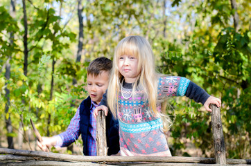 Kids in Autumn Outfit Playing at the Wooden Fence