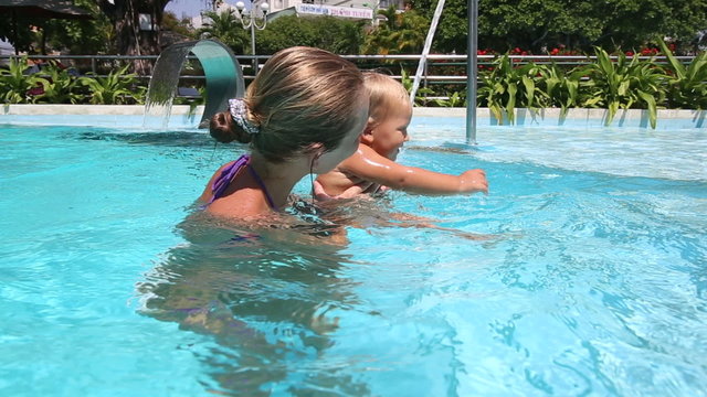 blonde little girl plays and laughs in city swimming pool