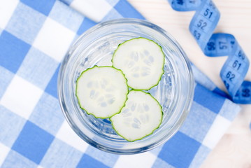 Glass of water with slices of fresh cucumber on a checkered napk