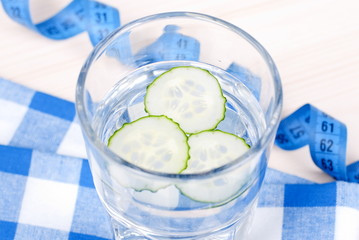 Glass of water with slices of fresh cucumber on a checkered napk