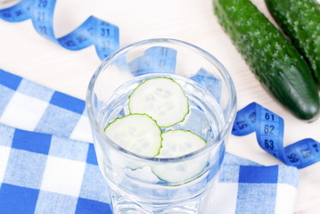 Glass of water with slices of fresh cucumber on a checkered napk