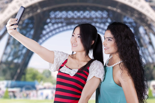 Two girls taking photos at Eiffel Tower