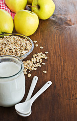 Homemade yogurt with apples and oatmeal on wooden table.