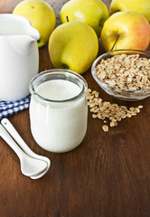 Homemade yogurt with apples and oatmeal on wooden table.