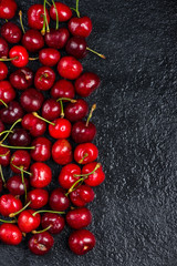 Fresh ripe organic cherries on black border  background