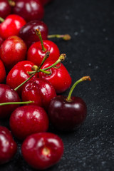 Fresh ripe organic cherries on black border  background
