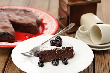 Piece of chocolate pie with whole blueberries and icing sugar in