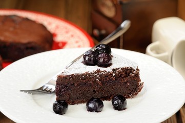 Piece of chocolate pie with whole blueberries and icing sugar in