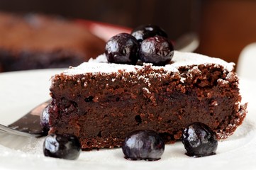 Piece of chocolate pie with blueberry and icing sugar in white p