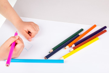 Child drawing in sketchbook  with color pencils.