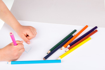 Child drawing in sketchbook  with color pencils.