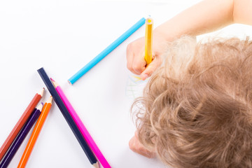 Child drawing in sketchbook  with color pencils.