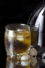 Glass with whiskey and a full whiskey bottle