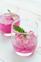 Pink Cocktail with fresh rose petals on wooden table